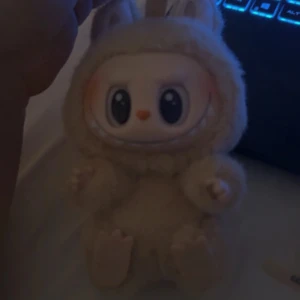 Labubu från Pop Mart - Söt beige Labubu Pop Mart, designad som tillbehör till sanning eller för att sätta på väskan, söt och  mjuk päls. Labubun har ett gulligt ansikte och är väldigt populär. Perfekt accessoar för dig som gillar unika och lekfulla detaljer. Äkthetsbevis finns. Säljer då jag letar efter en annan, 450, 400 vid snabbaffär. (Avklippt lapp/ej någon betydelse). Nyskick, bara öppnad och kollad på. 