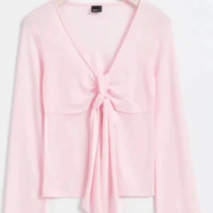 Ljusrosa långärmad topp med knyt - Säljer en ljusrosa långärmad topp med v-ringning och knyt framtill. Tunt och mjukt material som ger en feminin look. Perfekt att styla med jeans eller kjol.
