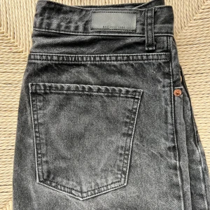 Svarta jeansbyxor från MNG - Säljer ett par svarta jeansbyxor från MNG med klassisk femficksdesign och knappar i gylfen. Jeansen har en rak passform och är tillverkade i denim.