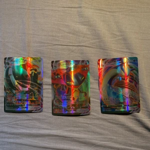 Pokémonkort VMAX - Copperajah, Dragapult, Lugia - Tre holografiska Pokémon VMAX-kort: Copperajah VMAX (340 HP), Dragapult VMAX (320 HP) och ett tredje kort som ser ut att vara Lugia. Alla har färgstark, glansig yta och är officiella Pokémonkort. Perfekt för samlare eller Pokémonfans!