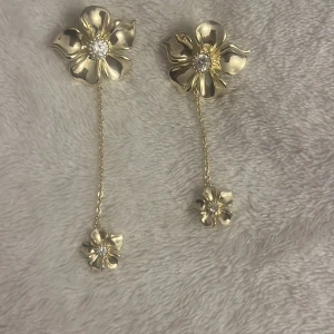 Guldiga blomörhängen ifrån IOAKU - Säljer ett par örhängen i guld med stora blommor från ioaku. De är helt oanvända och jag säljer dom eftersom att de inte kommer till användning. Pris kan diskuteras❤️