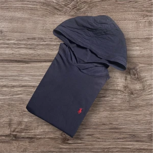 Ralph Lauren Hoodie – T-shirtmaterial (S) - Ralph Lauren Hoodie – T-shirtmaterial (S) 🖤  Säljer en snygg och äkta hoodie från Ralph Lauren i tunnare t-shirt-material – perfekt för våren eller sommarkvällar! Bekväm, stilren och lätt att matcha. 	•	👕 Storlek: S 	•	📏 Mått: Längd 67 cm, armhåla till armhåla 50 cm, axel till axel 43 cm 	•	🎨 Färg: Mörk 	•	🧵 Material: Tunn t-shirtkvalitet 	•	💸 Billigt pris på grund av defekt (se sista bilden) 	•	✅ Äkta Ralph Lauren  📍 Finns för avhämtning i Linköping eller skickas mot fraktkostnad. Hör av dig vi