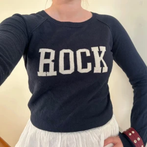 Mörkblå Zadig-tröja med ROCK-tryck - Mörkblå tunnare stickad tröja från Zadig & Voltaire med ”ROCK”-tryck, ribbade muddar/halslinning och små slitsar på sidorna. Materialen är bomull och kashmir. Inte märkt med någon storlek men uppskattas till XS/34 💙🎸⚡️