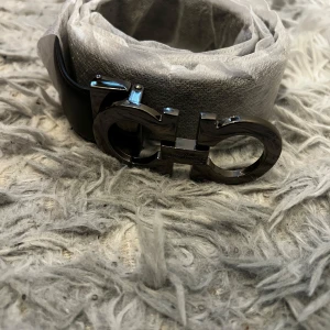 Ferragmo bälte  - Säljer ett svart bälte från Salvatore Ferragamo med en ikonisk metallspänne i silverfärg. Bältet är gjort i skinn och levereras med originalförpackning, dustbag och kvitto. Perfekt accessoar för att lyfta din outfit.