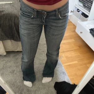 Blå bootcut jeans - Säljer ett par klassiska blå bootcut jeans med lätt slitning och normal passform. Jeansen har fem fickor, dragkedja och knapp framtill. Perfekta för en avslappnad stil. 