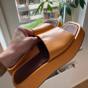platåsandaler - Säljer ett par trendiga oramgea/aprikos sandaler med platåsula och fyrkantig tå. I veganskt läder. Något smala i storleken annars true to size. Har några märken på sidorna (se bilder) 