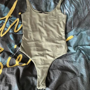 Olivgrön body - Säljer en olivgrön body från Bik Bok i storlek XS Modellen har smala axelband och något hög skärning vid benen. Man kan se på tredje bilden att den är lite nopprig men de är inget som stör, men säljer pågrund av att den inte används