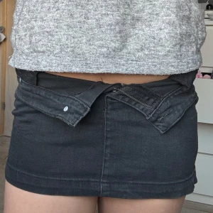 Svart jeanskjol  - Svart jeanskjol med knapp och dragkedja framtill. Snygg och enkel att matcha till olika stilar. Lappen med storleken är bortklippt men skulle säga s