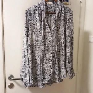 Mönstrad skjorta från Rojada XL - Snygg långärmad skjorta från Rojada i storlek XL. Skjortan har ett unikt svartvitt abstrakt mönster, klassisk krage och knäppning framtill. Materialet känns lätt och luftigt, perfekt för dig som gillar en stilren men ändå cool look.