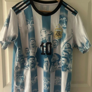 Argentina Messi 10 fotbollströja - Säljer en ikonisk Argentina fotbollströja med Messi 10-tryck. Tröjan har svart krage, svarta axelband. Perfekt för dig som älskar fotboll och Messi. Kan sänka priset vid snabb affär