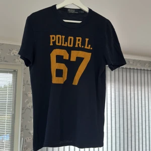  Ralph Lauren T-Shirt | Marinblå - Marinblå T-Shirt från Polo Ralph Lauren. Perfekt till sommaren. Skicket är som nytt och tröjan har inga defekter. Storleken är M men passar även S eller L beroende på hur man vill att den ska sitta.