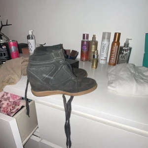 Gråa sneakers med kilklack - Snygga grå sneakers med kilklack och ljusbrun sula. Skorna har snörning framtill och är gjorda i mocka med perforerade detaljer och vita sömmar. Tror klacken är ungefär 5cm, jag vet inte om det är Isabelle marant eller inte har inte bra koll på modet. Jag har storlek 38 i alla skor men dessa är i 36 och passar mig. Dom är typ grå, mörk gröna.