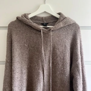 Brun stickad hoodie från Lindex - Mysig brun stickad hoodie från Lindex med luva och snörning. Tröjan har lång ärm och är tillverkad i ett fluffigt, mjukt material som känns extra skönt under kyliga dagar. 