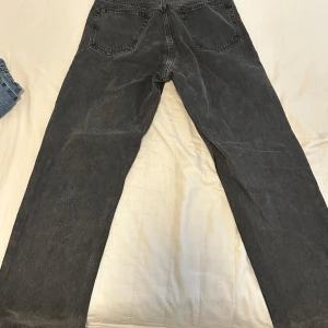 Svarta raka jeans i vintage-stil - Snygga svarta jeans med rak passform och klassisk femficksdesign. Jeansen har en något tvättad look som ger en cool vintage-vibe. Perfekta till sneakers eller boots och funkar året runt. Materialet är robust denim som håller formen.