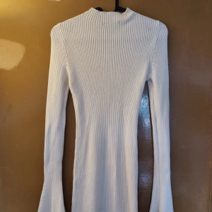 Brige ribbad långklänning Gina Tricot - Långärmad beige ribbad långklänning från Gina Tricot i stickad bomullsmix. Klänningen har utsvängda ärmslut och en figurnära passform med hög hals. Perfekt för dig som gillar stilrena och bekväma plagg med en modern twist. Nypris 600. Använd 2 gånger