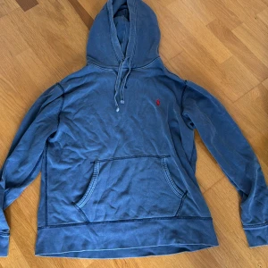 Blå hoodie från Polo Ralph Lauren - Säljer en blå hoodie från Polo Ralph Lauren Denim & Supply. Tröjan har huva med snörning, känguruficka och är tillverkad i mjuk bomull. Perfekt för en chill och avslappnad stil. Färgen är stone wash blue snygg vintage färg 