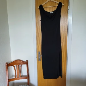 Svart långklänning Josefine HJ - Svart långklänning från Josefine HJ med draperad halsringning och ärmlös design. Klänningen har en snygg slits på sidan och är tillverkad i ett mjukt, stretchigt material som faller fint längs kroppen. Storlek s men jag är 38 så stor i storleken. 