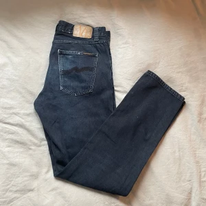 Nudie Jeans Gritty Jackson Black Forest - Snygga mörkblå jeans från Nudie Jeans, modell Gritty Jackson. Klassisk femficksdesign med raka ben och hög midja. Jeansen är tillverkade i 100% bomull och har en cool tvättad look med Nudie-logga på bakfickan. Storleken är 30/32. Lite tecken på användning men i bra skick. Bara att skriva om man har några frågor🤗🤗