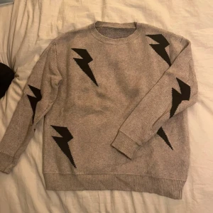 Beige stickad tröja med svarta blixtar  - Beige stickad tröja med svarta blixtar