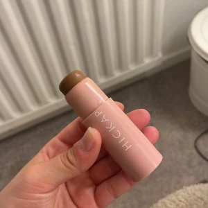 Hickap Bronzer Stick - Bronzer och contour stick från Hickap i färgen Hot Chocolate. Kommer i en smidig rosa tub med vridfunktion. Krämig formula som är lätt att blenda ut för en naturlig solkysst look. Perfekt för att skulptera ansiktet och ge värme till din makeup.