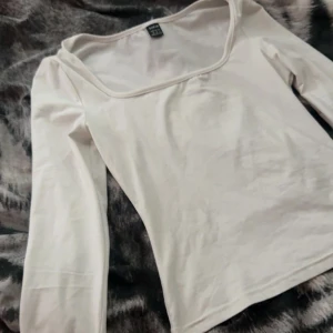 Vit långärmad topp från SHEIN - En stilren vit långärmad topp från SHEIN i storlek XS. Toppen har en fyrkantig urringning och är figurnära i modellen. Perfekt att matcha med jeans eller kjol för en clean look. Tillverkad i mjuk bomullsmix som känns skön mot huden.