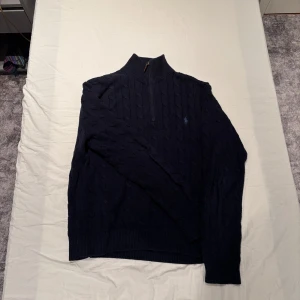Kabelstickad tröja Polo Ralph Lauren - Bekväm kabelstickad 1/4 zip från Polo Ralph Lauren. Mörkblå, tjock och varm. Mycket bra skick. Passar om du är runt 185cm lång. Hör av dig om du har någon fråga.