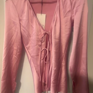 Rosa topp med snörning - Supersöt rosa satin knyttopp från Zara med långa ärmar och snörning framtill.🩷🩷Aldrig använd.