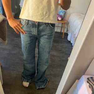 Zara bootcut/wide leg jeans låg midja blå 36 - Säljer ett par blå bootcut jeans från Zara i modellen ZW Low Waist Full Length. Jeansen har låg midja, klassisk femficksdesign och är tillverkade i bomull. Snyggt avslappnad passform med utsvängda ben och cool vintagekänsla.