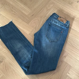  Replay Pattie jeans - Snygga blå jeans från Replay, modell Pattie. Jeansen har en mellanblå tvätt med lätt slitning och detaljer i rött vid sömmarna. Pris kan diskuteras 