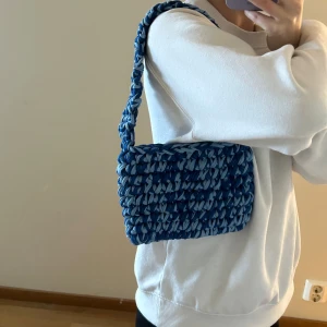 Virkad väska i blåa nyanser - Hemmavirkad handväska, gjord i t-shirtgarn som är gjort av textilindustrins tygöverskott.   Mått: ca 22cm bred, 15cm hög och 36cm hög (inklusive handtag)