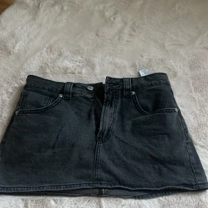 En svart/mörkgrå jeanskjol  - Den är i nytt skick men har fått ett svart streck på sig, störs inte jättemycket men säljer även för att den är lite för tight på mig.