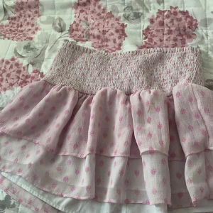 Rosa volangkjol med mönster - Supersöt rosa kortkjol med volanger och små rosa blommor. 299 tror jag e original priset 