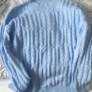 Ljusblå kabelstickad tröja - Superfin ljusblå kabelstickad tröja med klassiskt mönster och ribbade muddar. Tröjan har rund halsringning och långa ärmar, perfekt för lager-på-lager och chill stil. Mjuk och skön känsla, passar till jeans eller kjol. 