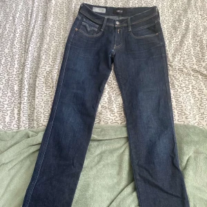 Replay Anbass mörkblå jeans - Snygga mörkblå Replay Anbass jeans med klassisk femficksdesign och kontrastsömmar. Modellen har raka ben och normal passform, med coola detaljer på bakfickorna. Perfekt för dig som gillar stilrena och tidlösa jeans i jeansmaterial. Pris ej hugget i sten!!