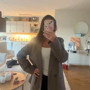 Brun rutig oversized kavaj - Snygg brunrutig kavaj med oversized passform och breda axlar. Jackan har klassisk krage, två knappar framtill och långa ärmar. 