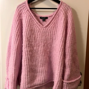 Rosa stickad tröja med v-ringning Amisu - Mysig rosa stickad tröja från Amisu med v-ringad hals och grovstickad struktur. Tröjan har långa ärmar och en relaxed passform, perfekt för att hålla sig varm och snygg under kyliga dagar.