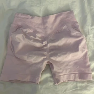 Ljusrosa seamless Impact  shorts - Säljer ett par ljusrosa seamless Impact shorts med hög midja och ribbad linning. De är stretchiga och sitter tight, perfekta för träning eller chill. Materialet känns mjukt och följsamt mot huden. Snygg och enkel design utan synliga loggor eller detaljer.