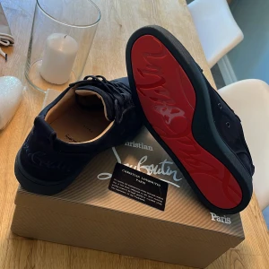 Mörkblå sneakers från Christian Louboutin - Snygga mörkblå sneakers i mocka från Christian Louboutin med ikonisk röd sula och broderad logga på hälen. Skorna ligger ute för 3000 men pris kan diskuteras de är bara att lägga förslag eller skriva. Storlek 43 men passar 42. Säljer för dom är en storlek för små för mig. Skorna är i nyskick aldrig använda utomhus endast testade hemma.