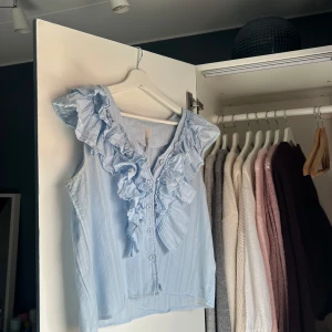 Ljusblå volangblus - Så fin blus med volanger från Eli White. Storlek S och bra skick. Två fläckar som syns på de två sista bilderna men syns ej vid användning. Skriv vid frågor eller köp direkt💗