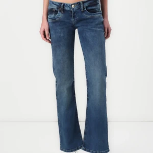 Blå bootcut jeans med låg midja - Snygga blå jeans med bootcut-snitt och låg midja. Jeansen har klassisk femficksdesign och är tillverkade i mjukt denimtyg. Perfekta för en avslappnad och trendig look.