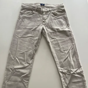 Beigea jeans från Gant - Snygga beige jeansbyxor från Gant med klassisk femficksdesign och raka ben. Byxorna har en stilren look med Gant-logga på bakfickan och är tillverkade i mjuk bomullsblandning. Perfekta för dig som gillar en clean och enkel stil. W30, L34 