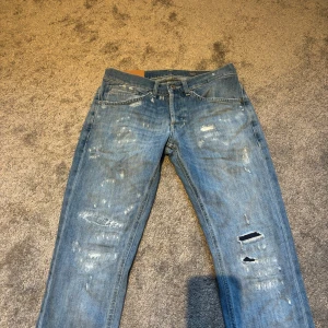 Dondup Jeans slitningar - Säljer ett par blå Dondup George jeans med slitningar på benen. Jeansen har klassisk femficksdesign, samt det orangea märket ovanför bakfickan. Perfekta för hösten.                                                                Mitt pris: 699kr, priset går att diskutera!