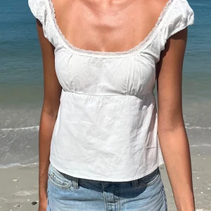 Söt Vit blus med spets och knytband Brandy Melville - Supersöt vit blus från Brandy Melville med spetskant som inte passar mig. Den är aldrig använd!