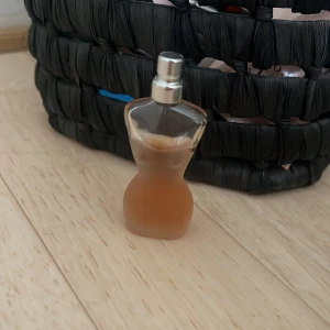 Jean Paul Gaultier Classique parfym - Ikonisk parfymflaska i frostat glas formad som en kvinnokropp, fylld med bärnstensfärgad doft. Silverfärgad spraykork. En klassiker med sensuell och unik design som verkligen sticker ut på hyllan.