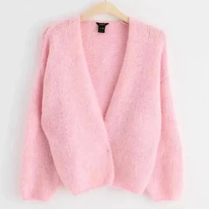 Ljusrosa fluffig kofta från Vero Moda - Supermysig ljusrosa kofta från Vero Moda med långärmad design och öppen framtill. Koftan är fluffig och stickad, perfekt för att ge din outfit en söt och chill vibe. Passar dig som gillar pastell och vill ha något extra mjukt i garderoben.
