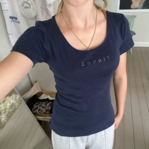 Mörkblå Esprit t-shirt med rhinestones - Assnygg mörkblå t-shirt från Esprit. Esprit-loggan i små pärlor ger en cool detalj. Passformen är slim och tyget är mjukt och skönt. Perfekt till jeans eller shorts, och har inga synliga defekter! Var en XL men är omsydd till ungefär S