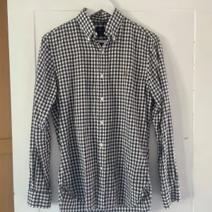 Rutig skjorta från Ralph Lauren S - Snygg slim fit skjorta från Ralph Lauren i svartvitt rutigt mönster. Klassisk krage, långa ärmar och knappar framtill. Broderad logga på bröstet. Perfekt för dig som gillar stilrena och tidlösa plagg. Skick 9/10
