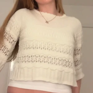 Vit croppad stickad tröja med hålmönster - Säljer en vit croppad stickad tröja med hålmönster och vågiga detaljer. Tröjan har trekvartsärm och är perfekt för lager-på-lager. Enkel och stilren design som passar till mycket så snygg från mango perfekt till allt!!💞💞💞💞💞.
