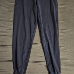 Blåa träningsbyxor Moving Mindfully - Blåa träningsbyxor från Moving Mindfully med dragkedjeficka. Tillverkade i stretchigt material med 75% polyester och 25% spandex. Perfekta för gymmet eller löprundan, med smal passform och bekväm midja.