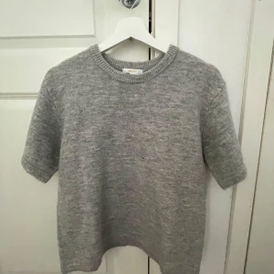 Grå stickad T-shirt - Säljer en enkel och stilren grå stickad T-shirt. Perfekt för lager-på-lager eller sommarens svalare dagar. Passar till det mesta och är superbekväm. Från Gina Young i storlek 170 är super fin och jätte skönt!! Skriv för fler bilder eller om du vill diskutera priset!!